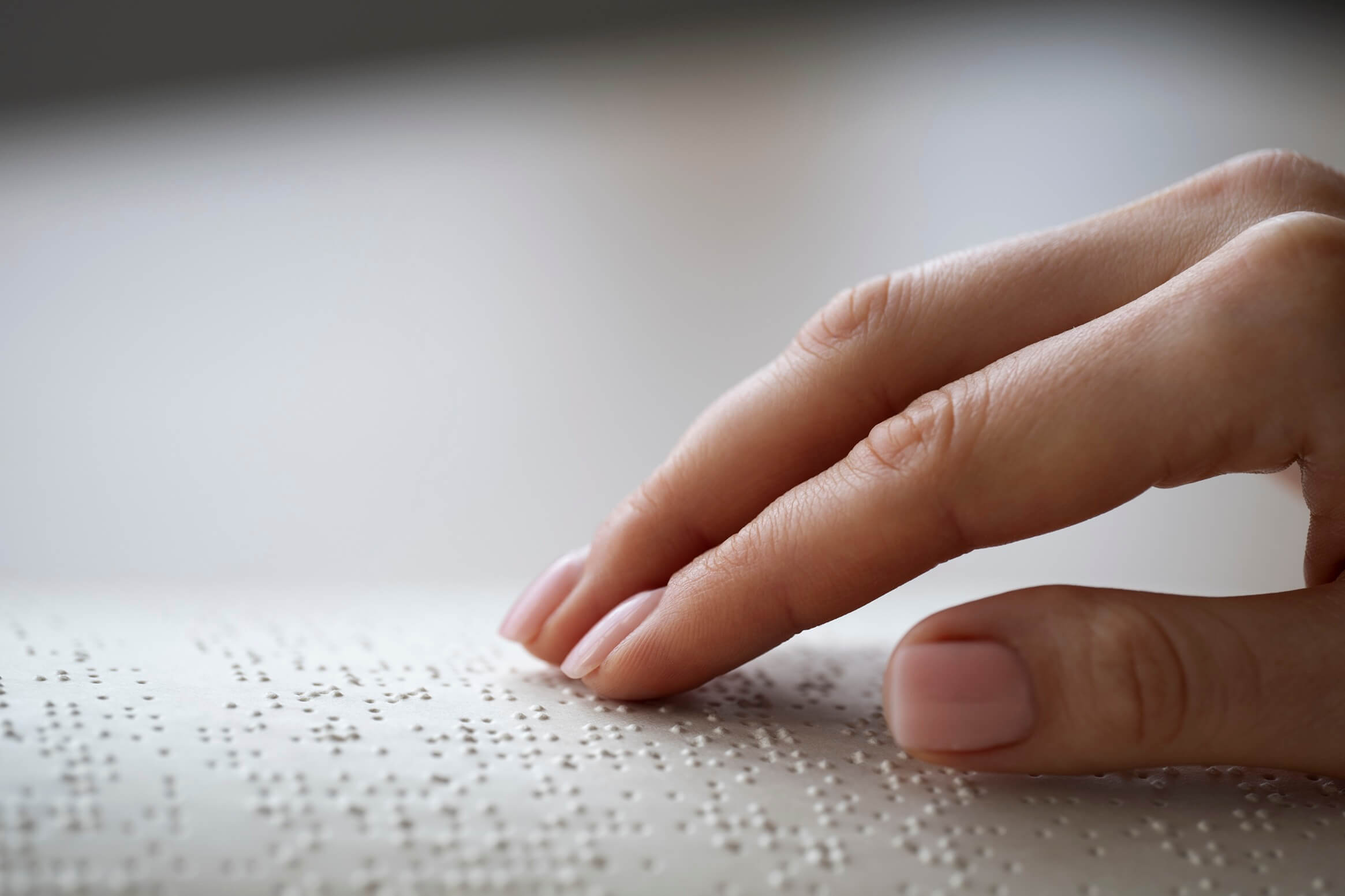 Una donna sfiora con le dita un libro in braille